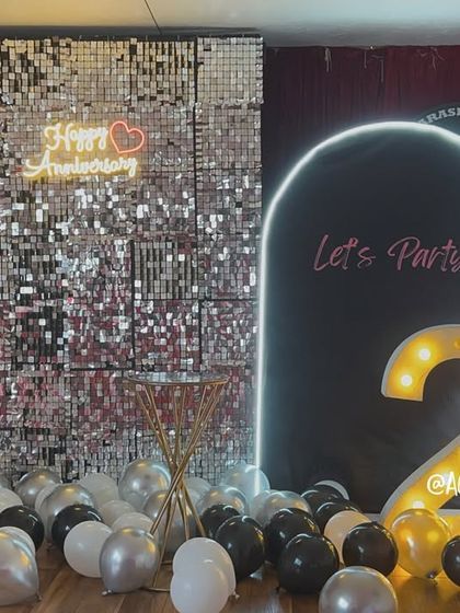 The dual backdrop setup with marquee numbers and balloons, ready for the party to begin.