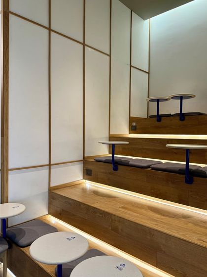 The standout feature of the Beanly cafe is the stepped seating, designed to utilize the triple-height space. This dynamic arrangement, complete with cushions and integrated tables, creates an informal lounge area that reflects the brand's easy-going philosophy.