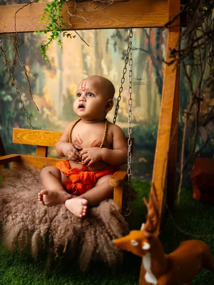Looking up with wonder, this little one embodies a sense of divine curiosity. The swing and forest backdrop create a beautiful, natural scene.