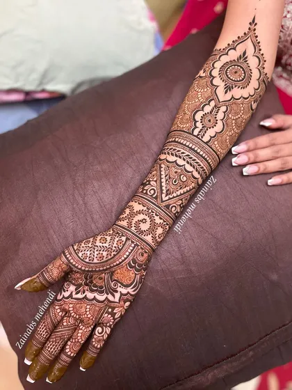 A full-length view of Arsha's bridal arm, showcasing a design that combines traditional bands with large mandala motifs.