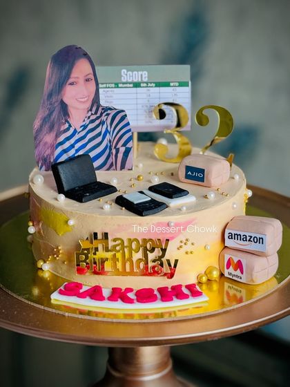 A fun and personalized cake for someone in the e-commerce world, featuring logos like Amazon and Myntra, a laptop, and even a performance scorecard.