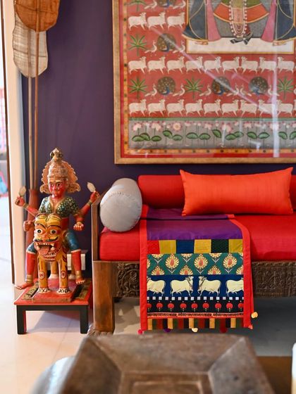 The reversible runner styled on a diwan, placed beneath a large Pichwai painting, showing a thematic connection in the decor.