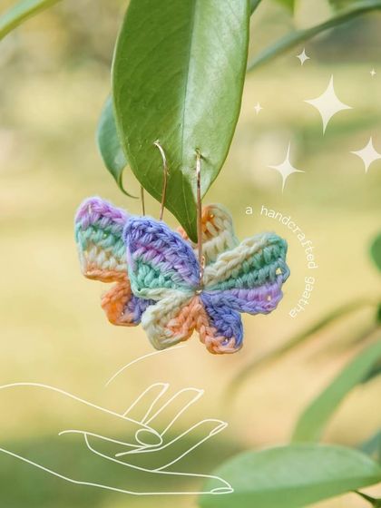 A styled shot of the multi-color 'Titli' earrings hanging from a leaf, looking like they're ready to take flight.