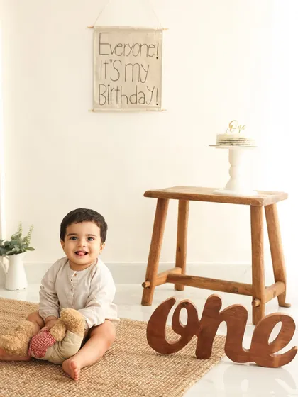 One year old and full of smiles. Before the cake smash, I always take some classic portraits to mark the occasion. This simple, rustic setup with a "one" sign is perfect for capturing your baby's personality.