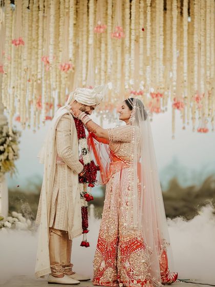 The exchange of garlands. This classic shot captures the essence of the Varmala ceremony, with the beautiful floral decor and soft smoke creating a dreamy and romantic atmosphere.