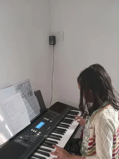 A young student practicing her keyboard lesson, carefully reading the sheet music.