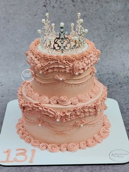 A delicate country classic vintage cake for a 13th birthday. This two-tiered peach-colored cake features beautiful ruffle piping and is topped with a sparkling crown.