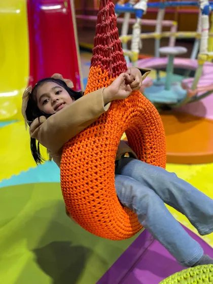 A guest enjoys a ride on one of our unique tire swings, a fun and playful element within our soft play zone.