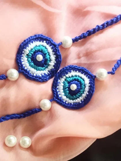 A close-up of our evil eye rakhis, showing the detailed crochet work in shades of blue, white, and turquoise. These are a sustainable and reusable alternative to traditional rakhis.