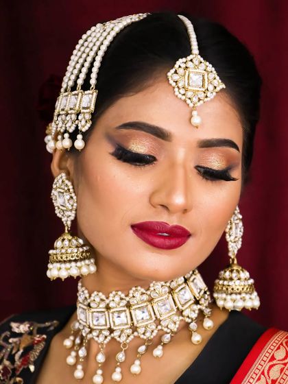 A stunning bridal look featuring a golden cut-crease, a bold red lip, and dramatic lashes. This is a perfect example of soft glam with a touch of classic bridal elegance.