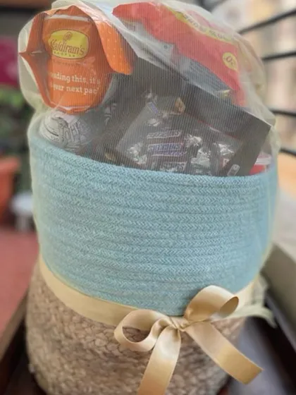 A beautiful two-toned jute basket filled with an assortment of goodies. Wrapped in a delicate net with a gold ribbon, this hamper is ready to be delivered as a wonderful surprise.