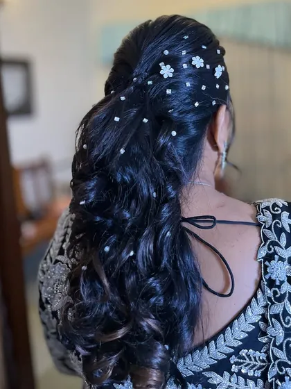 A chic and classy ponytail hairstyle, perfect for a wedding guest. The hair is adorned with delicate pearl flowers, adding a touch of elegance to the look.