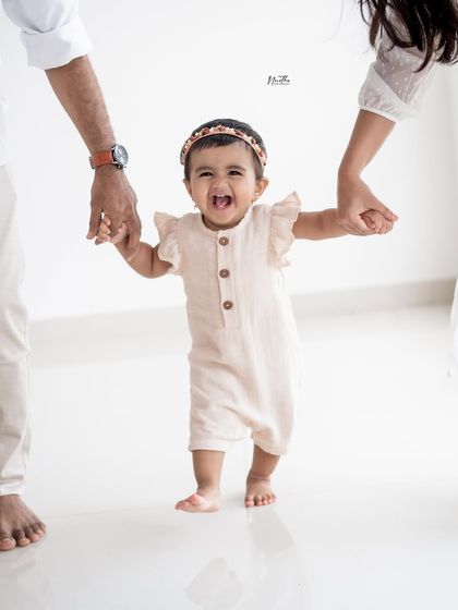A baby's first steps! Holding onto mom and dad's hands, this little one is full of excitement. A huge milestone to capture.