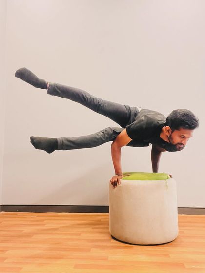 A flying splits variation (Eka Pada Koundinyasana) on a prop. The elevation adds a new dimension of challenge to this dynamic arm balance.