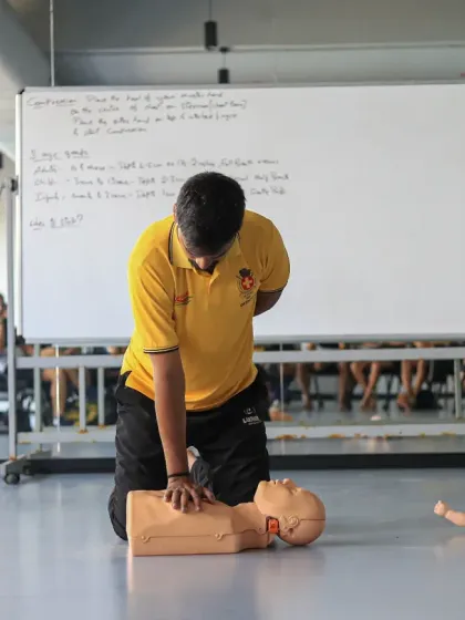 A coach's responsibility goes beyond the field. This image from our 'Restart a Heart' workshop shows a participant practicing essential CPR chest compressions on a manikin, a skill that can save a life.