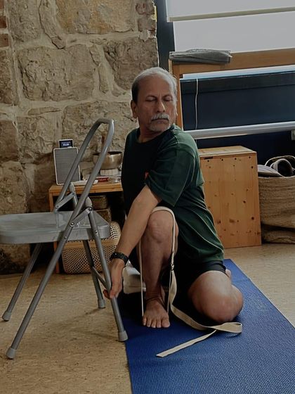 A seated twist, Bharadvajasana, using a chair for leverage. The chair helps to deepen the twist through the thoracic spine while keeping the hips grounded.