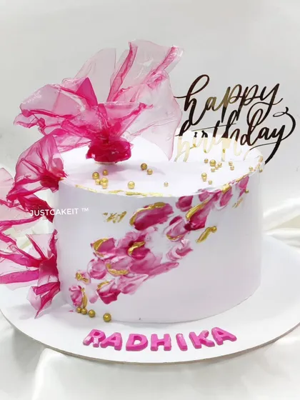 An abstract cake with a beautiful splash of pink and gold. The design is finished with a dramatic, edible rice paper sail.