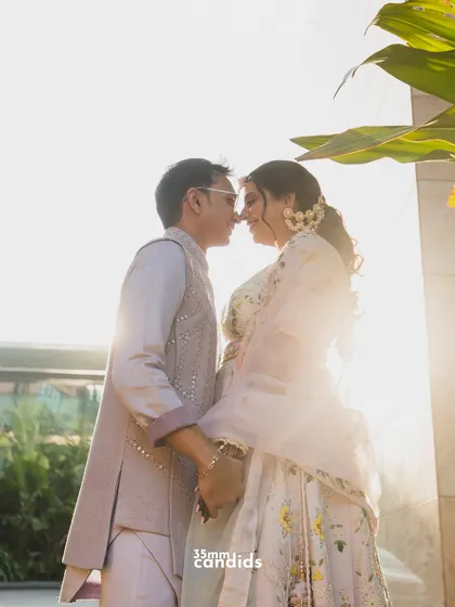 A sun-kissed portrait of the couple at their Haldi ceremony. The golden light filtering through the leaves adds a magical glow to this romantic moment.