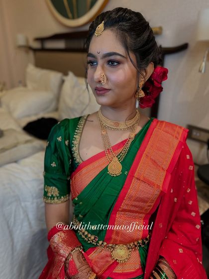 A full view of the bridal attire, showing how the makeup, hairstyle, and saree draping come together. The red and green combination is a classic choice for Maharashtrian brides.