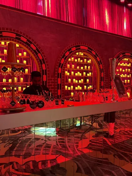 A close-up of the candle-lit bar, showcasing the intricate design of the arched back panels and the warm, inviting glow they cast on the space.