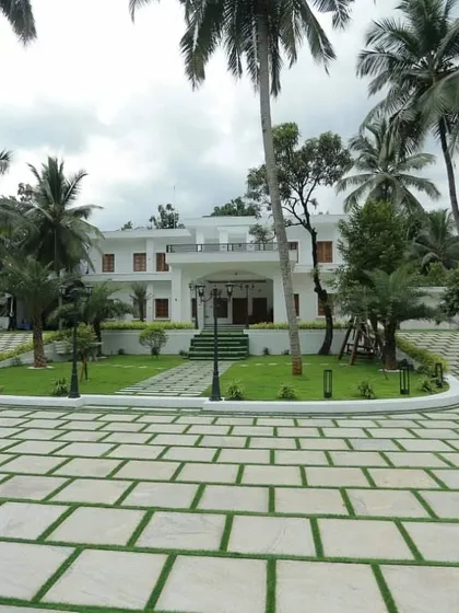 For this large property, we designed a grand entrance with a paver driveway interspersed with grass. This hardscaping technique is both visually striking and eco-friendly, flanked by manicured lawns, palm trees, and elegant lighting for a resort-like feel.