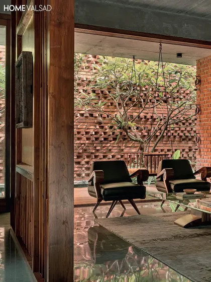 Looking from the interior living space out into a courtyard. The perforated brick wall allows for light and air circulation while providing a beautiful backdrop for the trees, demonstrating how landscape and architecture can work together.