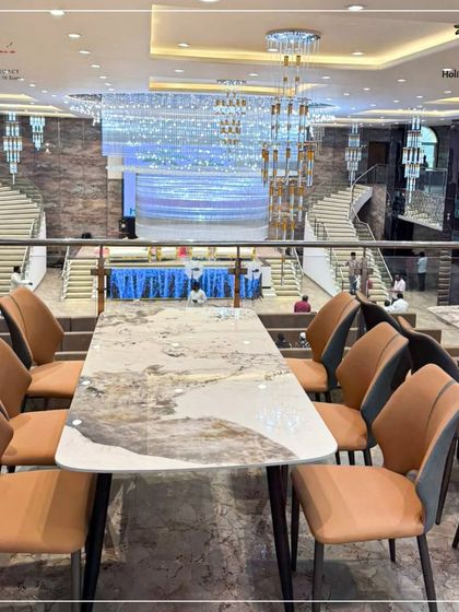 The mezzanine level of our Karjat hall offers an exclusive dining or viewing area. This image shows a modern marble-topped dining table overlooking the main hall, providing a VIP experience for special guests during the celebration.