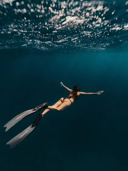 A freediver glides into the deep blue of the Caribbean Sea. The image conveys a sense of freedom and belonging in the vastness of the ocean.
