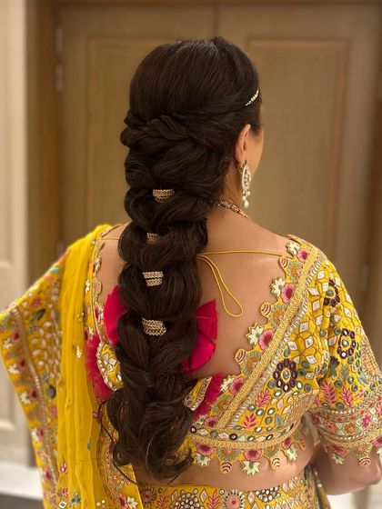 The groom's mom, all set for a traditional night in Udaipur with this stunning, thick braid accessorized with golden cuffs.