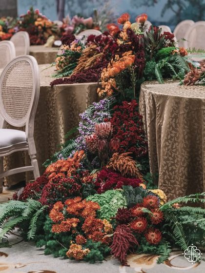 A cascading floral runner flows from the main table in our 'Orchard of Life' setup. The deep reds, oranges, and greens create a feeling of natural abundance and celebration.