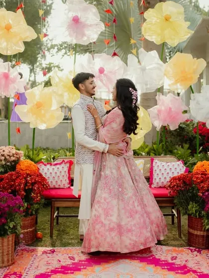 A romantic shot of the couple in the midst of the colorful Mehendi garden. The backdrop of giant paper flowers and lush blooms creates a dreamy, fairytale-like setting.