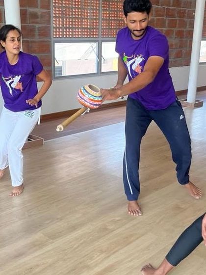 An instructor uses a Caxixi, a shaker, while teaching a movement. The rhythm guides the pace and style of the game.