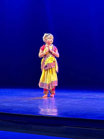 A young Bharatnatyam dancer in a moment of quiet devotion on stage. We teach our students that dance is not just movement but also a form of spiritual expression.