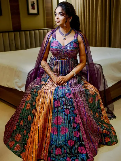A full-length shot of Shloka's vibrant Sangeet lehenga. The makeup was designed to complement the multi-colored outfit, with a focus on glowing skin and defined eyes.
