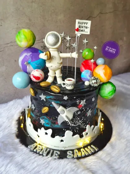 A cake for a dreamer who loves space and coffee. This galaxy-themed cake features a hand-painted cosmic design, edible planets, and a custom astronaut figurine holding a tiny coffee cup, blending two passions into one delicious creation.