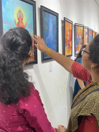 Art lovers closely examining the intricate details of paintings on display at the Chitrakar exhibition.