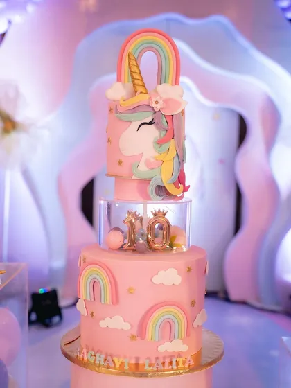 A beautiful unicorn-themed cake with a rainbow topper and intricate details.