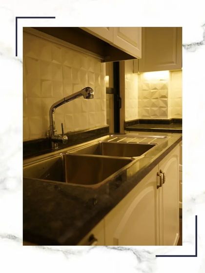We pay attention to every detail, including the kitchen sink. This image shows a high-quality double-bowl stainless steel sink with a modern faucet, set against a textured tile backsplash.