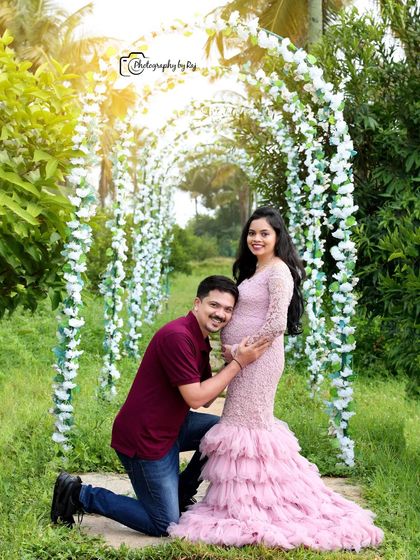 A classic pose with the father-to-be listening to the baby's heartbeat. The floral archway and the mother's pink lace gown create a romantic setting.