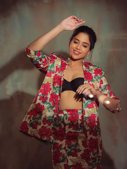 A playful and dynamic shot of Karunya Krishnasamy. Her messy bun and confident pose perfectly match the bold floral suit.