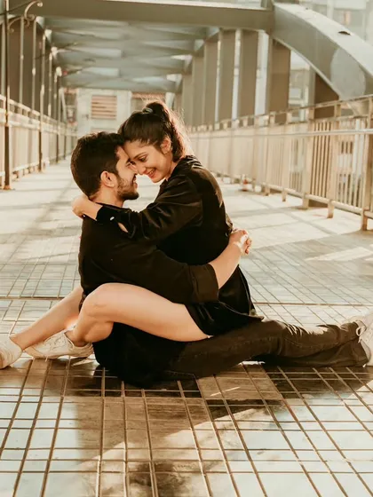 A candid and affectionate moment on a Mumbai footbridge. This relaxed pose shows the comfortable, easy love between the couple, set against an urban backdrop.