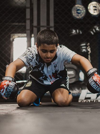 A young fighter kneels in a moment of focus during the Wai Kru. This ritual teaches discipline and mental preparation, which are just as important as physical skill.