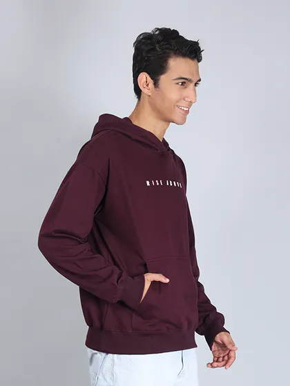 A side-profile shot of a model in a hoodie, smiling. This angle shows the fit on the arms and torso while also conveying a relaxed, positive mood.