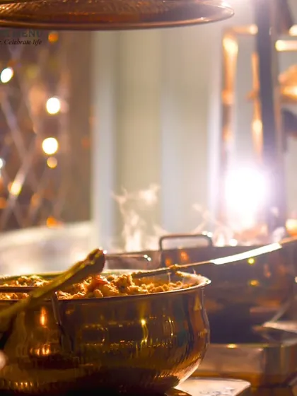 Steam rising from hot food in traditional copper serving dishes, creating an inviting and appetizing scene at the buffet line.