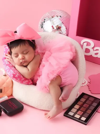 Pretty in pink. With a big pink bow and a fluffy tutu, this newborn is ready for her Barbie-themed debut. The setup includes miniature accessories to complete the playful, high-fashion look.