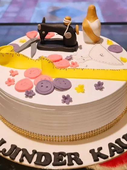 A cake that's tailored to perfection for a sewing enthusiast. This design features a miniature fondant sewing machine, measuring tape, buttons, and scissors, celebrating a beloved craft.