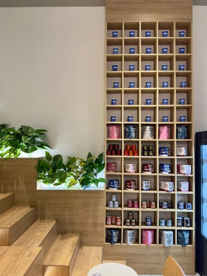 The merchandising unit at Beanly is a key brand identifier. This tall, grid-like shelf is visible from every corner of the cafe, showcasing the colorful product range and serving as a storage installation for personalized customer cups.