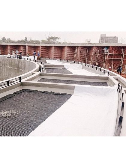 Workers laying waterproofing and drainage systems on the roof of the memorial, preparing it for the green roof installation.