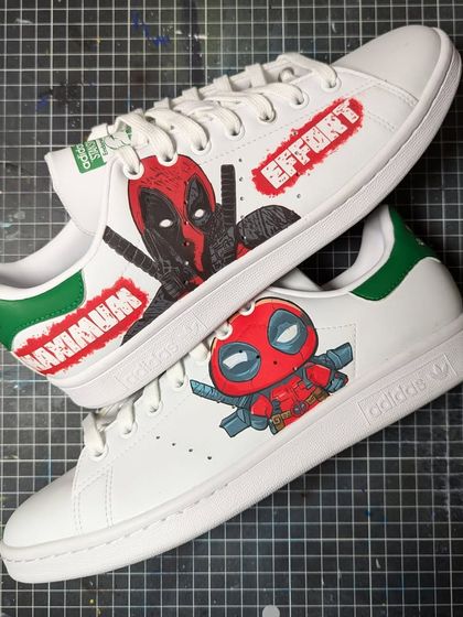 "Maximum Effort" on a pair of Adidas Stan Smiths. This Deadpool custom features his classic look on one shoe and a cute chibi version on the other.