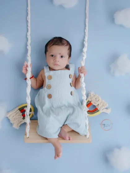 A wider angle of the cloud swing setup, showing the full composition and the baby's adorable, relaxed pose.